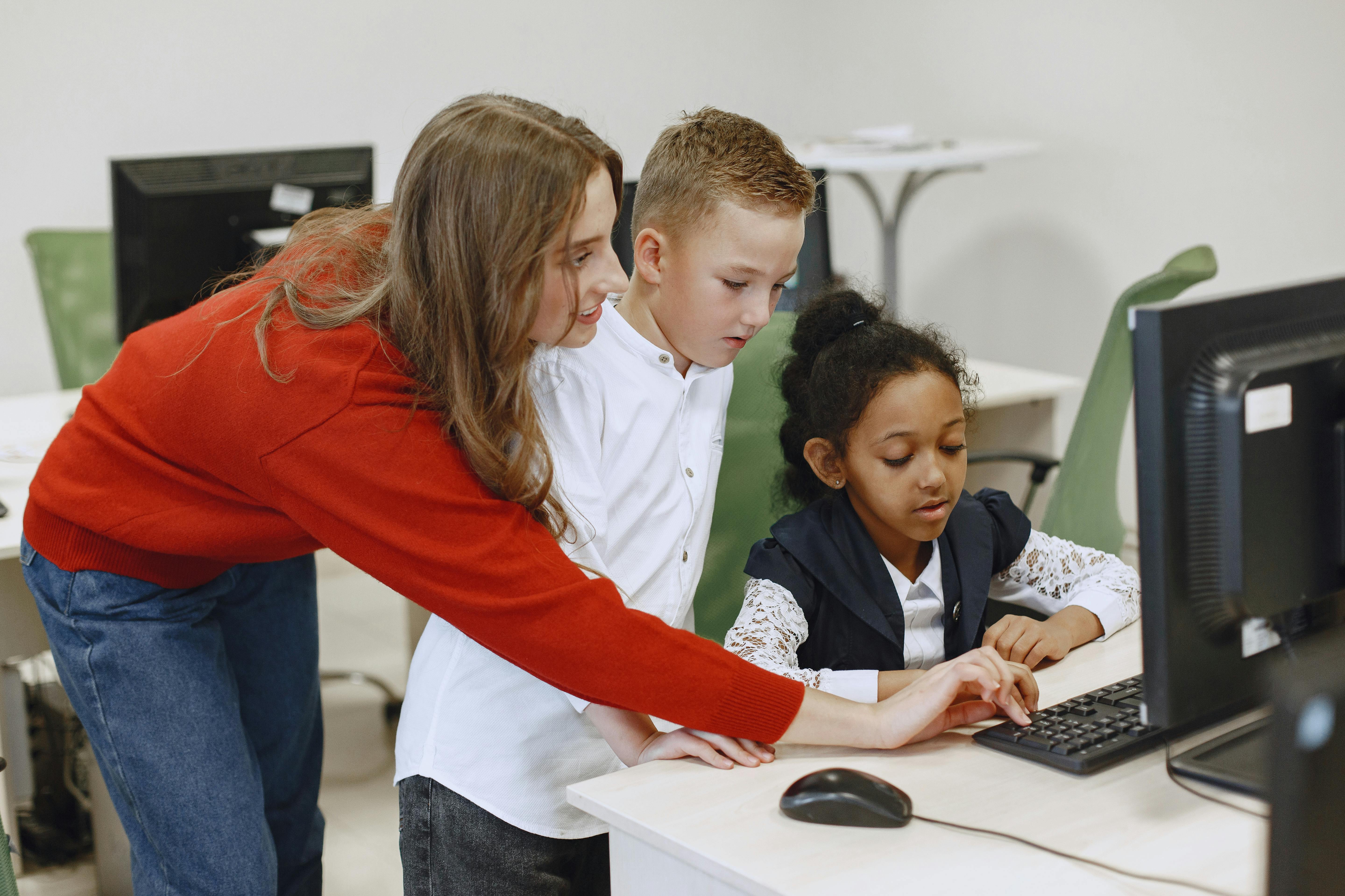 Teacher guiding pupils on safe computer use in school